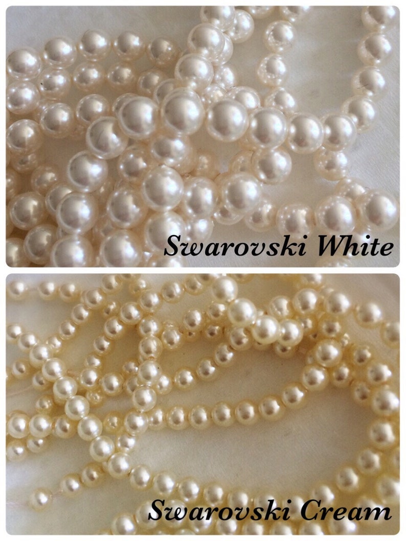 May include: Two strands of white pearl beads, one strand is labeled "Swarovski White" and the other is labeled "Swarovski Cream".