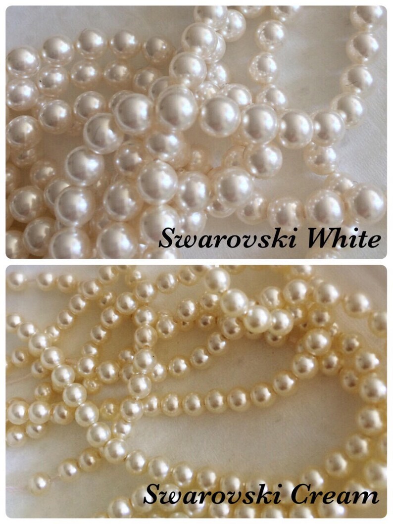 May include: Two strands of white pearl beads, one strand is labeled "Swarovski White" and the other is labeled "Swarovski Cream".