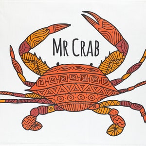 May include: A white kitchen towel featuring a detailed illustration of a crab with orange, yellow, and maroon patterns. The text "MR CRAB" is above the crab. The crab design is centered on the towel.
