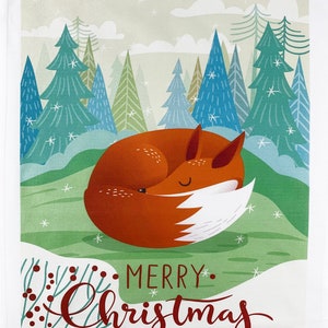 May include: A decorative Christmas-themed tea towel featuring a sleeping fox in shades of orange and white, curled up on a green grassy hill. The background includes stylized evergreen trees in blue and green, with the words "MERRY Christmas" in red script.