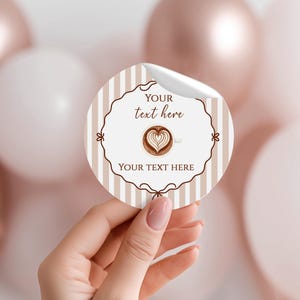 May include: A circular sticker featuring a coffee cup design and the text "YOUR text here". The sticker has a striped beige and white background, with a decorative brown border. The coffee cup has a heart-shaped design in the foam.
