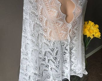 May include: White lace shawl with a scalloped edge and intricate pattern. The shawl is draped over a mannequin and is made of delicate, lightweight fabric.