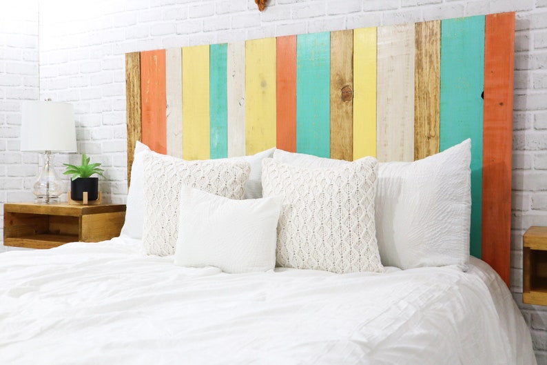 Full size multi-colored boho style wood panel floating headboard with natural brown base wood stain, peach, off-white, yellow and mint hues,  paired with matching floating nightstands in a golden brown finish