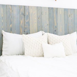 May include: A white bed with a blue and yellow wood headboard and white pillows. The bed is made with white sheets and a white blanket.