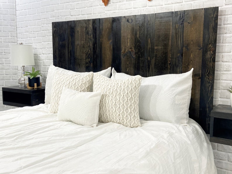 Partial view of a floating headboard queen size bed built with real wood planks tinted with a rich black oil-based stain. The headboard is paired with a minimalist dark wood stain floating nightstand.