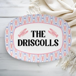 May include: Oval serving platter with a white center and the text "THE DRISCOLLS" in black. The platter has a pink border and is decorated with pink lobsters and a blue and pink pattern.