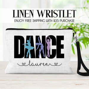 May include: White linen wristlet with a black zipper and a black strap. The wristlet has the word "DANCE" printed in black with a silhouette of dancers in the letters. The name "lauren" is printed in cursive below the word "DANCE".