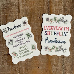 Pu&ograve; includere: Due carte rettangolari bianche con bordi smerlati, decorate con illustrazioni di tessere del Mahjong e testo. Una carta riporta Barbara, Charleston e le regole del gioco. L'altra recita Everyday I'm Shufflin' e Barbara con grafiche colorate.