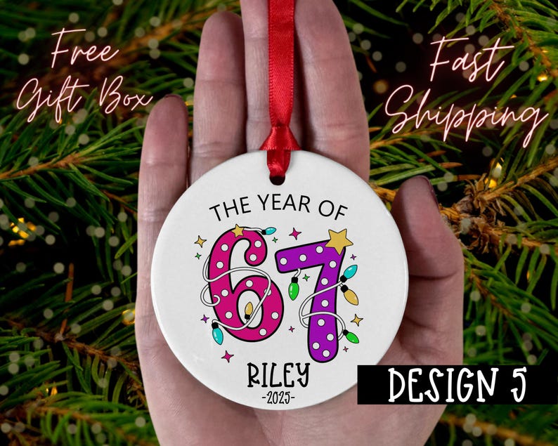 May include: A white ceramic ornament with a red ribbon, featuring the text "THE YEAR OF 67 RILEY -2023". The numbers are decorated with pink polka dots and purple polka dots, with colorful lights and stars. The design is labeled "DESIGN 5".