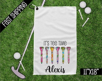 May include: White golf towel with a colorful golf tee design and the text "It's Tee Time" and "Alexis". The towel is 11 inches by 18 inches.