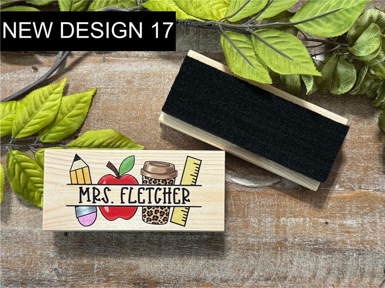 May include: Wooden teacher desk organizer with the text "MRS. FLETCHER" and school-themed illustrations. Includes a pencil, apple, coffee cup, and ruler. A separate wooden eraser is also present. The text "NEW DESIGN 17" is in the upper left corner.