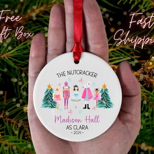 May include: White ceramic Christmas ornament with a watercolor illustration of characters from The Nutcracker ballet. The ornament features the text "The Nutcracker", "Madison Hall as Clara", and "~2024~".