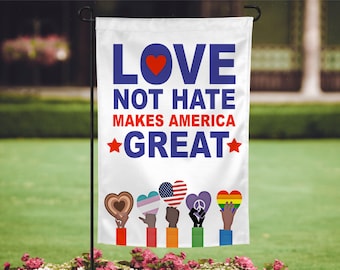 May include: A white garden flag with the words "LOVE NOT HATE MAKES AMERICA GREAT" in blue and red. The flag features a red heart and stars, along with hands holding heart-shaped symbols representing different communities.