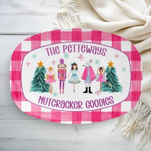 May include: Oval serving platter with a pink and white gingham border. The center features a Nutcracker-themed illustration with text that reads "The Petteways Nutcracker Goodies". The design includes Christmas trees and cartoon characters.