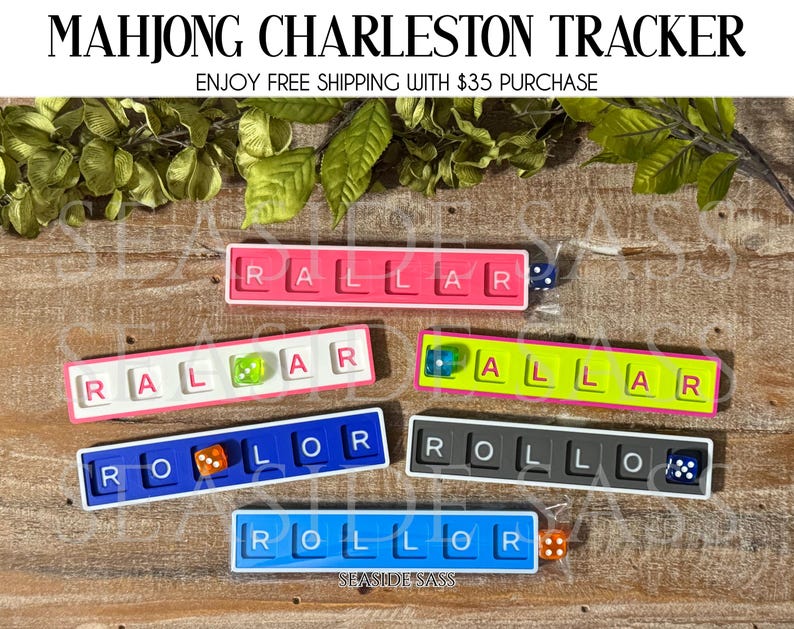 May include: Colorful Mahjong Charleston Tracker sets. Each tracker features a rectangular design with lettered tiles and a die. The trackers come in various colors, including pink, blue, yellow, and gray. The text "MAHJONG CHARLESTON TRACKER" is at the top.