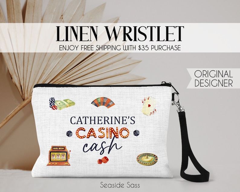 Puede incluir: Pulsera de lino blanco con cremallera negra y correa de mu&ntilde;eca negra. La pulsera tiene un dise&ntilde;o de tem&aacute;tica de casino con cartas de juego, dados, fichas y una m&aacute;quina tragamonedas. El texto en la pulsera dice "Catherine's Casino Cash".