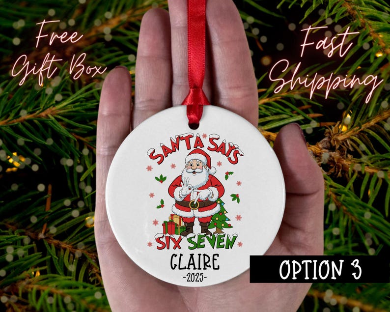 May include: A white Christmas ornament with a red ribbon, featuring Santa Claus and the text "SANTA SAYS SIX SEVEN CLAIRE -2023". The ornament has a festive design with red, green, and brown accents, perfect for holiday decor.