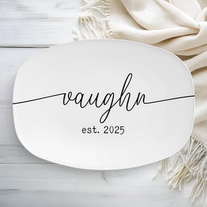 May include: White oval platter with the name "Vaughn" in a cursive font, with "est. 2025" below. The platter is on a white wooden surface with a cream-colored blanket in the background.