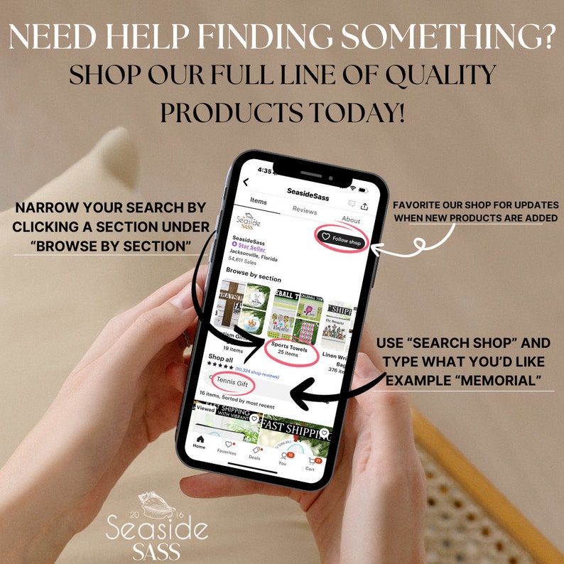 May include: A mobile phone screen displaying a shop's homepage with the name "Seaside Sass" and a variety of products for sale, including sports towels, tennis gifts, and linen wraps. The text "Browse by section" is visible on the screen. The phone is being held by a person's hands.
