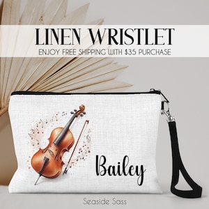 May include: White linen wristlet with a black zipper and wrist strap. The design features a watercolor violin with musical notes and the name "Bailey" in black script. The text "Linen Wristlet" is at the top.