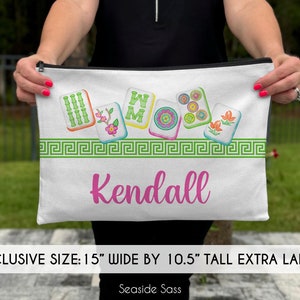May include: White canvas zippered pouch with a green, white, and red Chinese Mahjong tile design. The pouch is 15 inches wide by 10.5 inches tall and has the name "Kendall" printed in pink.
