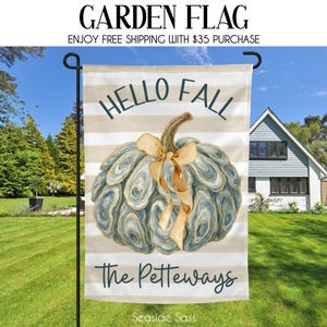 May include: A garden flag with a watercolor design. The flag features a blue and tan pumpkin with a bow, the words "HELLO FALL" and "The Petteways". The flag is on a black pole in a grassy yard.
