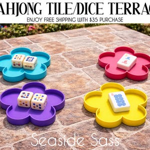 May include: Four flower-shaped trays in blue, pink, purple, and yellow, each holding Mahjong tiles or dice. The trays are on a brick surface. The text "MAHJONG TILE/DICE TERRACE" and "Seaside Sass" are visible.