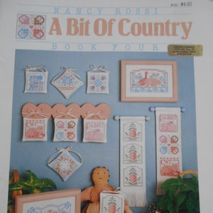 May include: A collection of cross-stitch patterns from the book "A Bit of Country, Book Four" by Nancy Rossi. The patterns include a variety of designs, such as a house, a pineapple, a cat, a rabbit, and a goose. The patterns are all in a country style and are perfect for adding a touch of charm to your home.