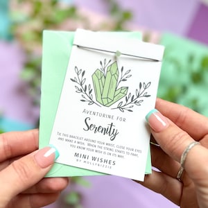 May include: A green aventurine crystal charm bracelet with a card that reads "Aventurine for Serenity. Tie this bracelet around your wrist, close your eyes and make a wish. When the string starts to fray, you know your wish is on its way. Mini Wishes by Molly&Izzie."