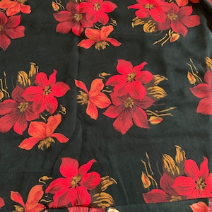 May include: Black fabric with a red floral pattern. The flowers are large and have a dark red center with lighter red petals.