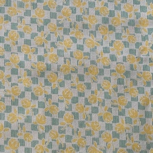 May include: White fabric with a repeating pattern of yellow flowers and green stripes.
