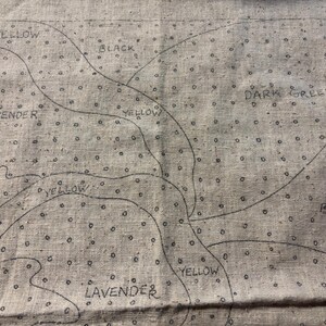 May include: A close-up of a fabric with a pattern of small dots and lines. The fabric is labeled with different colors, including yellow, black, dark green, and lavender.