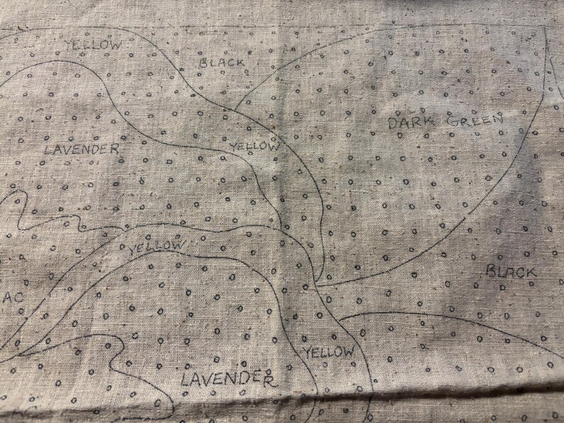 May include: A close-up of a fabric with a pattern of small dots and lines. The fabric is labeled with different colors, including yellow, black, dark green, and lavender.