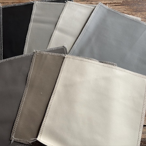 May include: A collection of fabric swatches in various shades of gray, brown, and beige. The swatches are arranged in a fan shape and have a subtle texture.