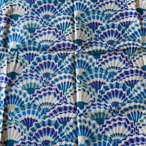 May include: A fabric textile featuring a repeating geometric pattern of stylized fan shapes in shades of royal blue, light blue, teal, and white. The design consists of layered, radiating segments that create a dense, interconnected visual texture.