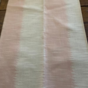 May include: A fabric swatch with a vertical stripe of pink and a white background. The fabric has a subtle texture.