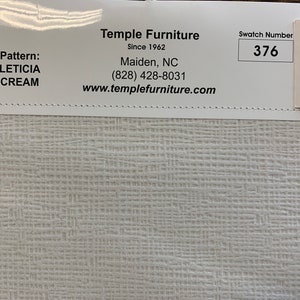 May include: A white fabric swatch with a subtle texture. The swatch is labeled "LETICIA CREAM" and has a swatch number of 376. The fabric is described as moisture-resistant, long-lasting, durable, easy to clean, and stain-resistant.