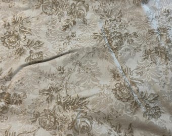 May include: Beige fabric with a repeating pattern of brown floral designs.
