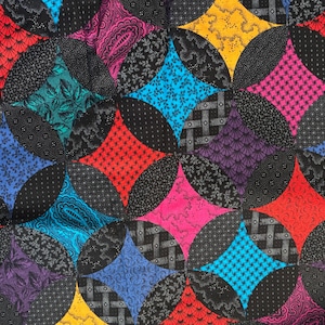 Op de afbeelding: Een stoffen quilt met een herhalend patroon van zwarte cirkels die elkaar kruisen om kleurrijke ruitvormen te vormen. De ruiten tonen diverse prints in rood, geel, magenta, taling, blauw en paars, met zwarte stoffen texturen.