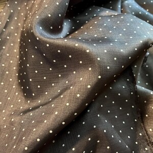 May include: A brown fabric with white polka dots. The fabric is folded and has a soft, silky texture.