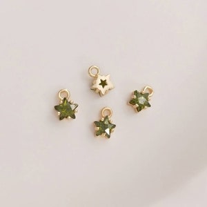 May include: Four gold star charms with green crystal accents. The charms have a loop at the top for attaching to jewelry.
