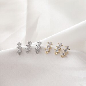 May include: Three pairs of jewelry findings with a row of three clear cubic zirconia stones. The findings are available in silver, gold, and rose gold.