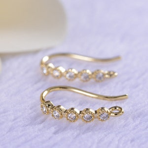 May include: Two gold earring hooks with a row of five clear round cubic zirconia stones.