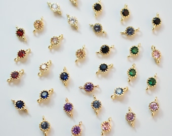 May include: Assortment of colorful gemstone connector charms with gold-tone settings. The charms feature a variety of colors, including red, blue, green, purple, and clear.