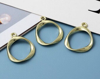 May include: Three gold-colored metal charms in the shape of a twisted oval ring. Each charm has a small loop at the top for attaching to a necklace, bracelet, or other jewelry.