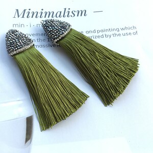 May include: A pair of green tassel earrings with a silver and black rhinestone embellishment at the top.  Minimalism - min. i. m.