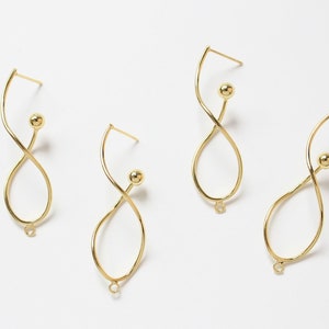 May include: Four pairs of gold-colored, abstract-shaped earrings. Each earring features a curved, elongated loop design with a small ball accent and a post for piercing. The earrings are displayed against a white background.