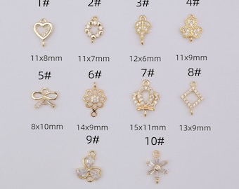 May include: A collection of ten gold-colored jewelry charms with various designs, including hearts, wreaths, leaves, clovers, bows, flowers, crowns, diamonds, and snowflakes. Each charm has a loop for attaching to jewelry. Sizes range from 8x8mm to 15x11mm.