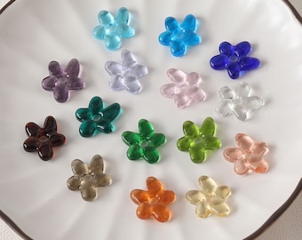 May include: Assortment of 15 glass flower beads in various colors, including blue, green, purple, pink, brown, and orange. The beads are all in the shape of a five-pointed flower with a hole in the center.