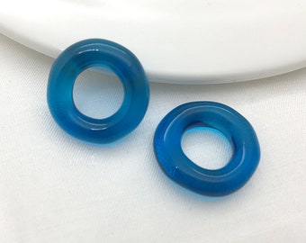 May include: Two turquoise blue glass ring shaped beads. The beads are smooth and glossy.